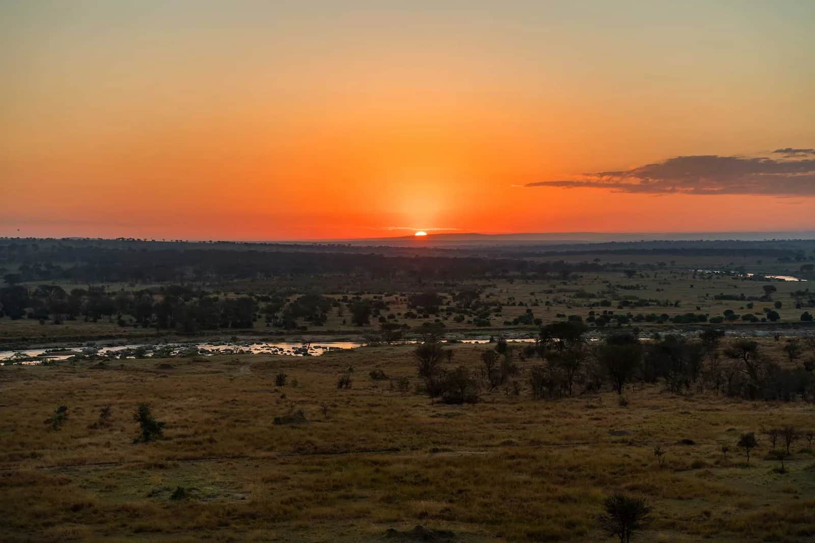 The sun setting over a wide river valley and open plains