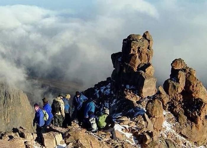 Group of trekkers with backpacks crossing rocky high-altitude terrain