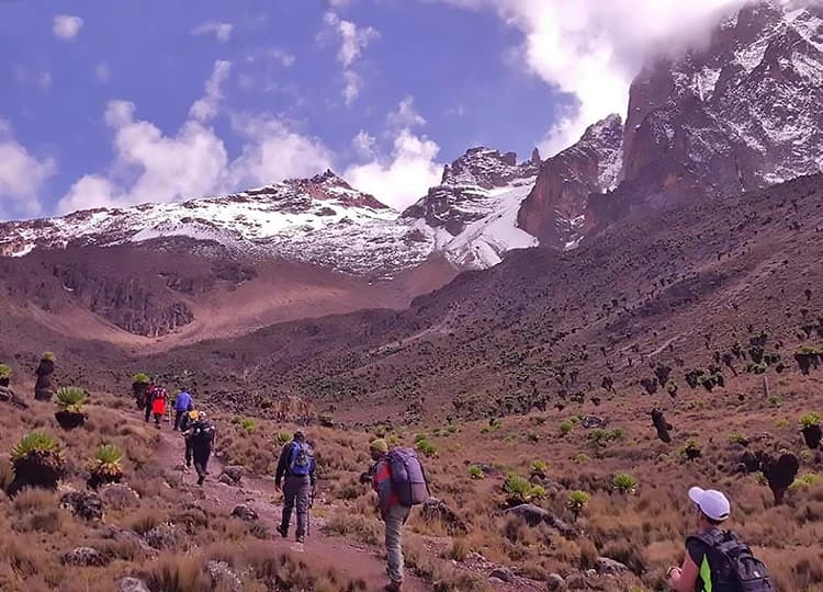 Group of trekkers walking through a broad high-altitude mountain landscape