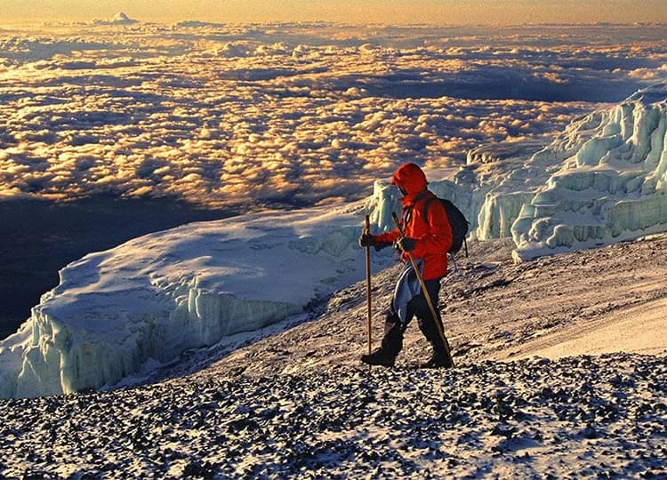 Trekker standing beside ice on a steep high-altitude mountain slope