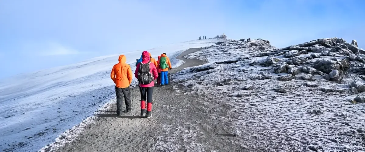 Trekkers walking along a snow-covered high-altitude mountain trail